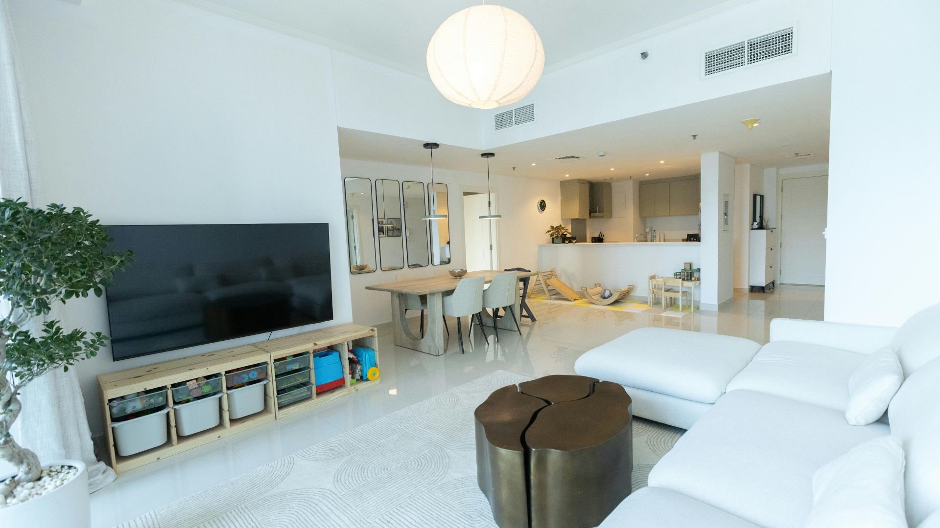 Modern, bright open-plan living space with white furniture and storage